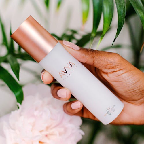 A hand holding AVYA Skincare travel moisturizer