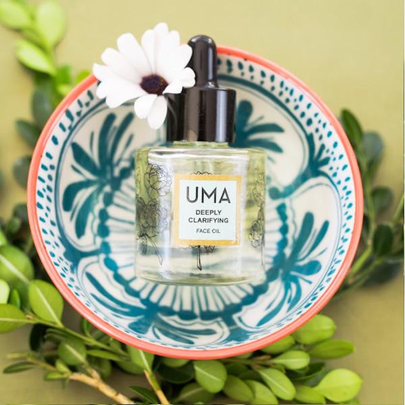 UMA deeply clarifying face oil bottle in a floral bowl