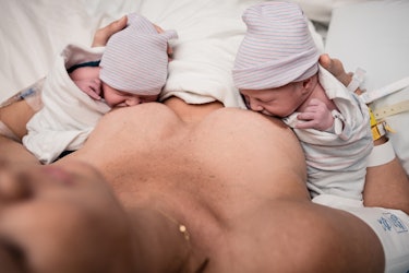 mom breastfeeding newborn twins swaddled at the hospital