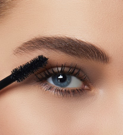 A close-up of a woman with blue eyes applying L'Oreal Paris Lash Paradise 