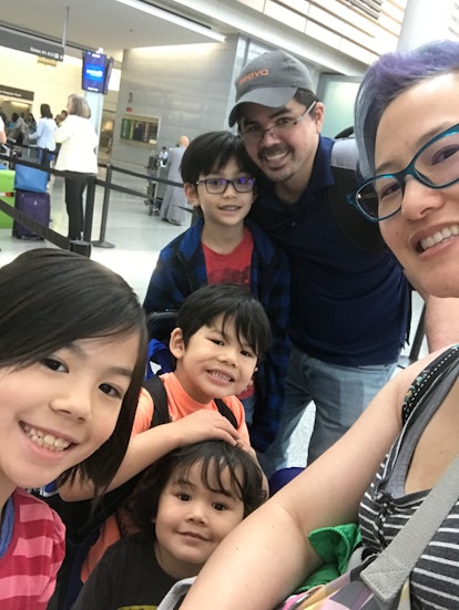 A mother taking a selfie with her four kids and husband at an airport