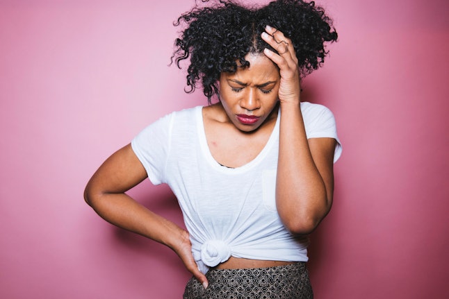 A woman with a PMS-related headache on a pink background. Period changes can be a sign your IUD has moved.