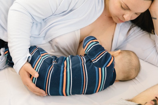 Mom breastfeeding her baby while it lays down on its mattress 