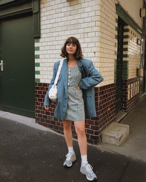 A woman in an oversized blazer, a dress and sneakers