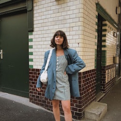 A woman in an oversized blazer, a dress and sneakers