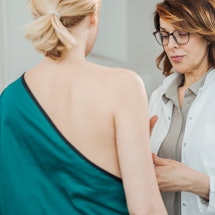 A doctor checking a woman because she has experienced less-common symptoms of breast cancer