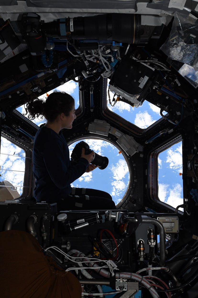 Christina sitting perched inside the Cupola of the International Space Station
