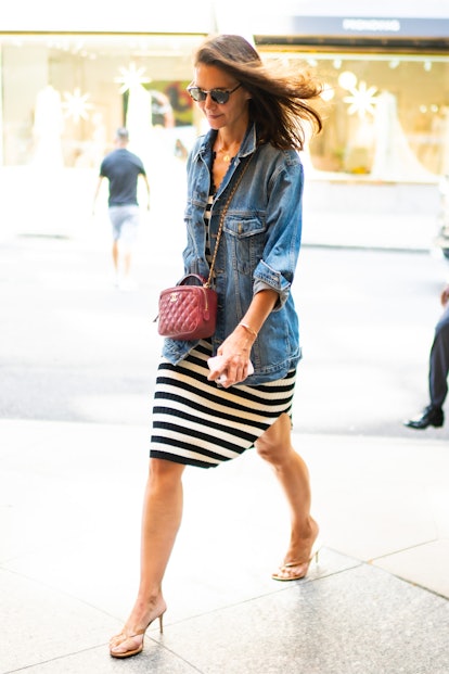 Katie Holmes in a jean jacket, a striped black and white skirt and white high heel sandals