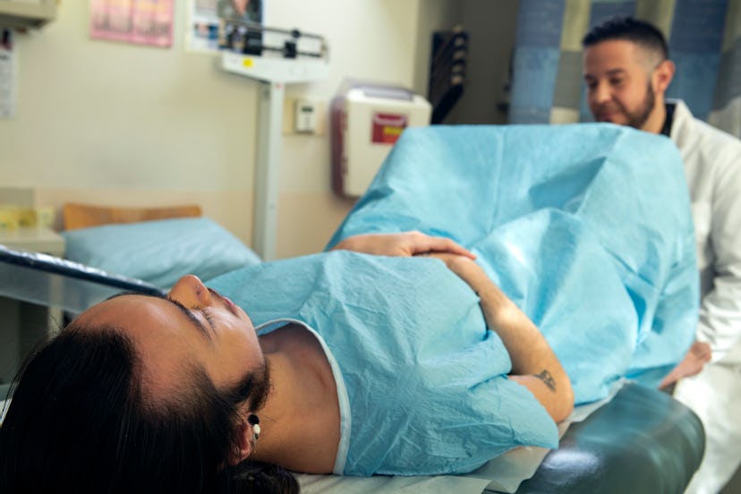 A young male with colorectal cancer lying while being examined by a doctor.