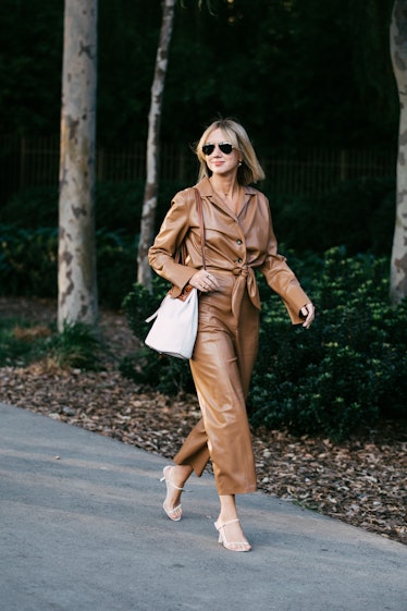 Moda Operandi’s Lisa Aiken going down the street wearing a brown leather suit and a white bag