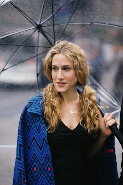 Sarah Jessica Parker as Carrie Bradshaw walking under an umbrella