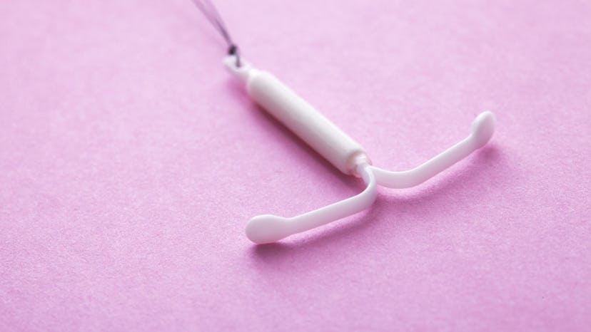 an iud on a pink background in an article about signs of pregnancy with an IUD