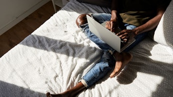 A person on their laptop in bed working from home 