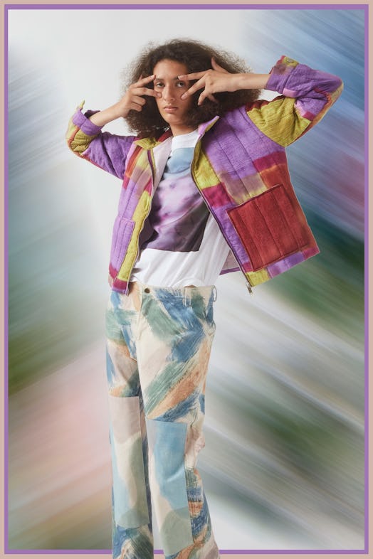 A model posing in a multicolored jacket, a shirt with an abstract picture and multicolored jeans des...