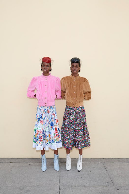 Two models wearing cool girl outfits, a sweater, skirt and hat by marc jacobs, while standing in fro...