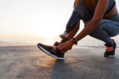 A closeup of a woman with a prosthetic leg getting her trainers ready for exercise which helps her w...