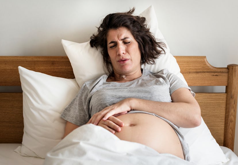 pregnant woman in pain on bed holding belly