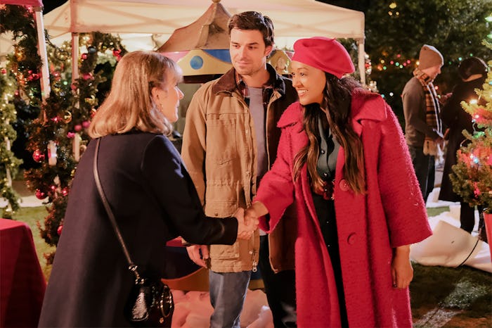 A scene from A Very Vintage Christmas of Tia Mowry shaking hands with someone while Jesse Hutch stan...