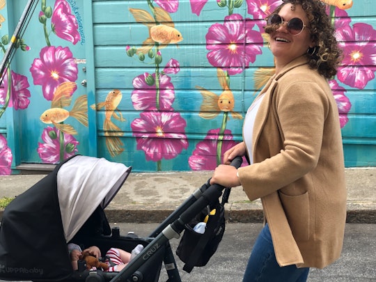 A woman pushing a stroller from wallmart in front of a wall with flower graffiti
