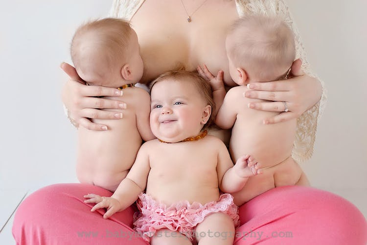 photo of mom holding triplets in lap, two of which are tandem nursing