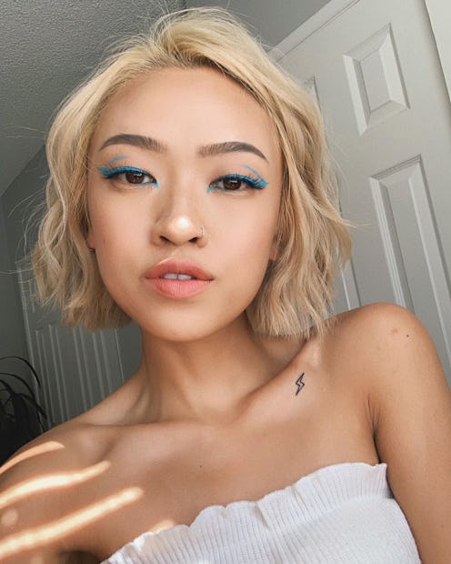 A woman with a blue neon eyeliner with prestige-level pigment