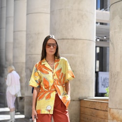 A woman posing in a hawaiian shirt, red pants and white sneakers