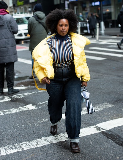 A woman in a striped top, yellow puffer jacket and dark blue denim jenas
