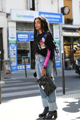 A woman in a black shirt with pink sleeves, baggy denim jeans, black boots and a black bag