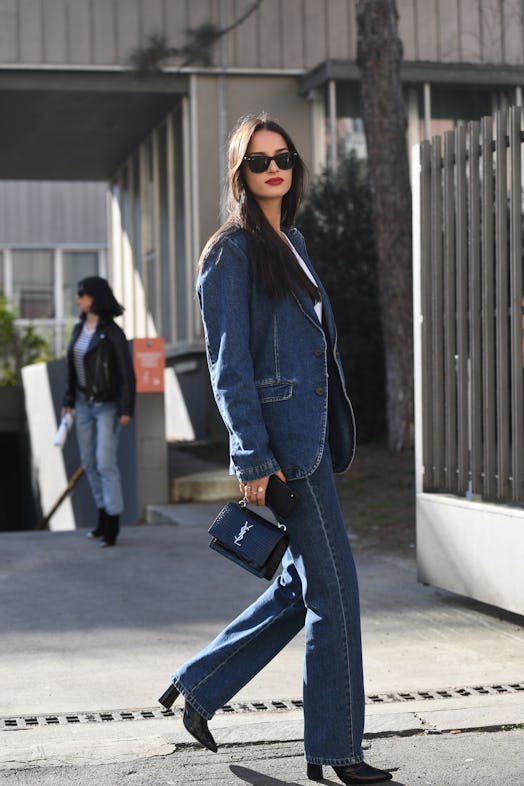 A woman in a blue denim suit, black heels and a small black bag