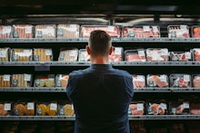 A man standing at the supermarket reading the food labels