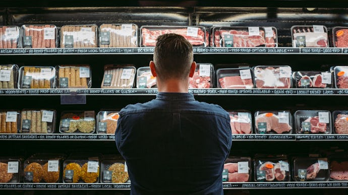 A man standing at the supermarket reading the food labels