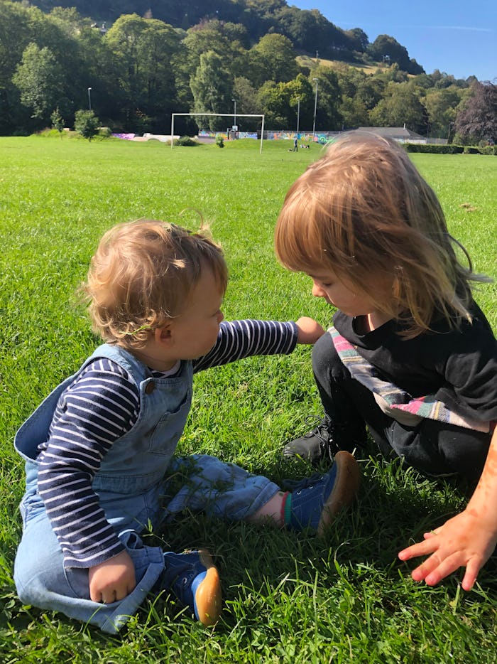 Two kids sitting on grass