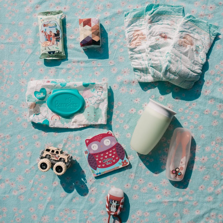 Wet wipes, a book, spoons, a sippy cup, a sanitizer and a car toy from a mom's bag 