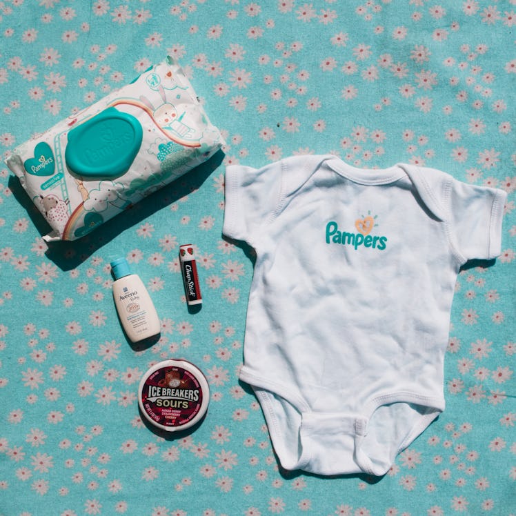 A onesie,  sunscreen, a snack along with Pampers diapers and wipes from a mom's bag 