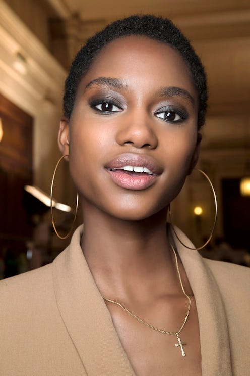 A model wearing eyeshadow available at Ulta, with a beige blazer and large hoop earrings