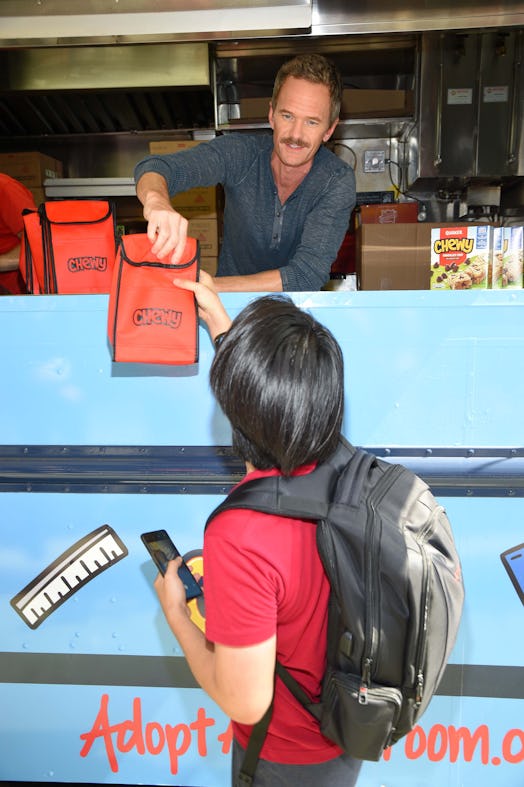 Neil Patrick Harris giving a red Quaker Chewy bag to a boy out of a food truck