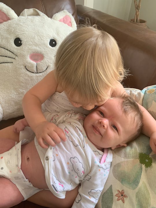 a baby and a toddler play on ground