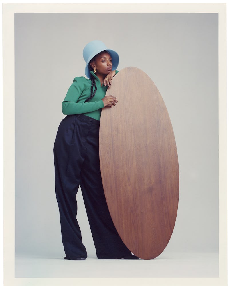 Mereba posing in a green Nina Ricci bodysuit, black trousers and a light blue hat