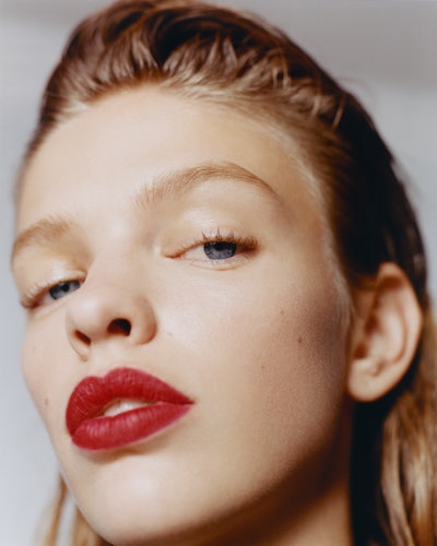Close up of a model posing with red lipstick and slicked back hair