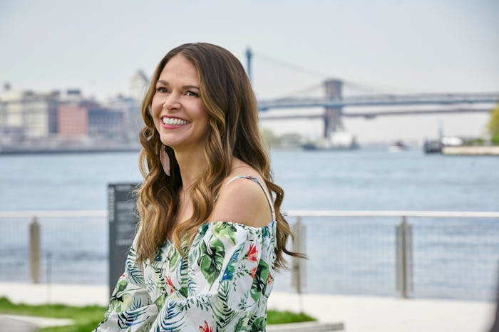 Sutton Foster smiling while posing for a photo in a floral blouse