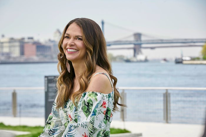 Sutton Foster smiling while posing for a photo in a floral blouse