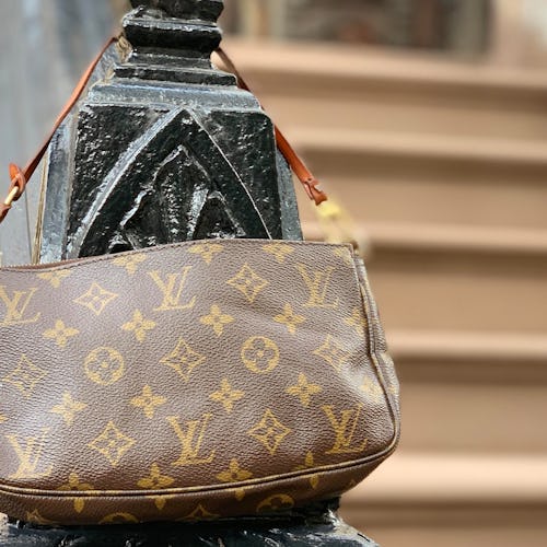 Brown Louis Vuitton pochette hanged on a stair railing