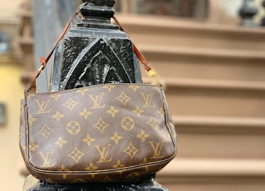 Brown Louis Vuitton pochette hanged on a stair railing