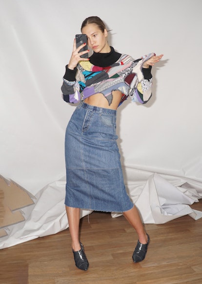 Ksenia Schnaider posing in her own brand while wearing a asymmetrical skirt and a colorful top