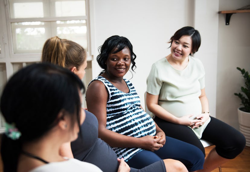 group of pregnant women smiling and sitting next to each other on chairs