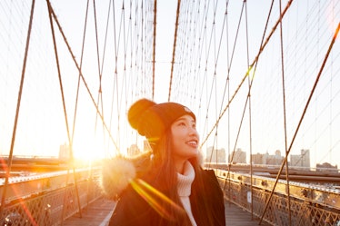 Young Asian woman crossing bridge in sunlight