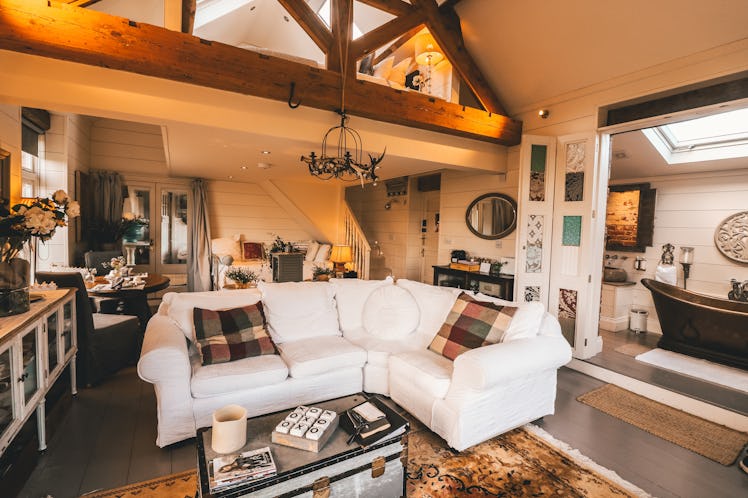 The interior of a luxury private barn in Cheshire, England features a white couch and cozy, romantic...