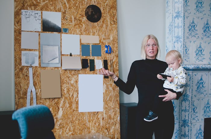 A baby holding a toddler points at a board during a meeting