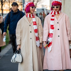 Two women in coats and matching hats and scarves in red-white as cold-weather accessories