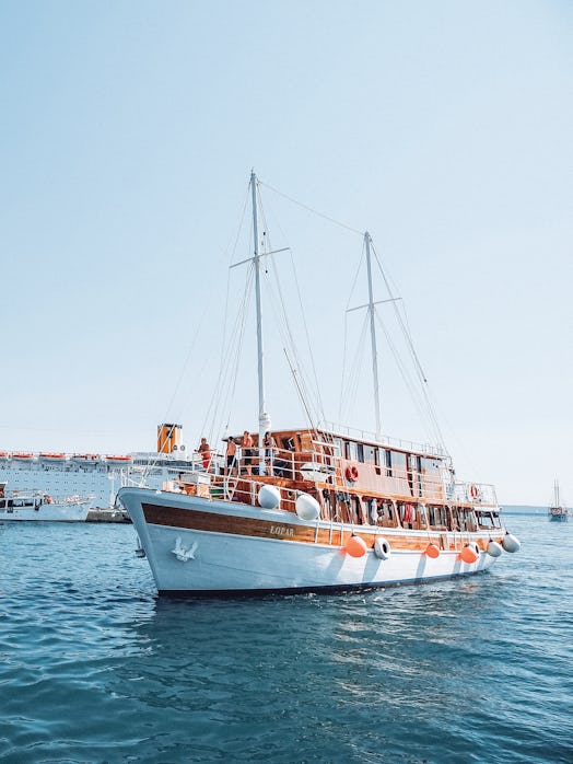 A boat with Contiki travelers on board sails through bright blue water in Europe during the summerti...